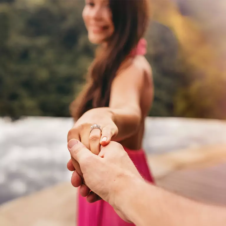 Beach proposal couple hold hands